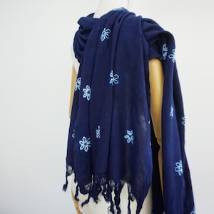 Peut inclure: Écharpe bleu marine ornée de motifs floraux bleu clair. Le tissu léger est drapé sur un mannequin. Les bords sont frangés. Idéale pour les journées plus chaudes, cette écharpe mesure environ 180 cm de long.
