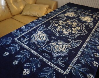 Könnte beinhalten: Eine marineblaue Tischdecke mit einem weißen Blumen- und Fischmuster. Das rechteckige Tuch hat ein detailliertes Design mit einem Rand aus Blättern und Blumen. Das Muster wiederholt sich über die gesamte Oberfläche.