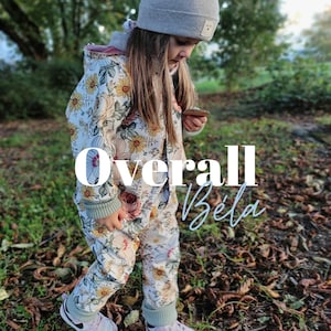 Könnte beinhalten: Ein weißer und grüner Blumen-Overall mit einer hellrosa Kapuze. Der Overall hat einen Reißverschluss und einen grün-weiß gestreiften Bund. Der Overall wird von einem Kind getragen, das in einem Blätterhaufen steht. Der Text "Overall Béla" ist über das Bild gelegt.