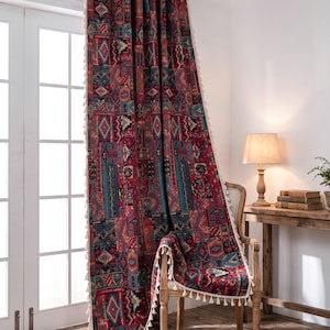 Puede incluir: Una cortina estampada con una mezcla de diseños geométricos rojos, turquesa y beige. La cortina tiene un borde con borlas y está drapeada sobre una silla de madera. El texto "LucyHomeDesign" es visible.