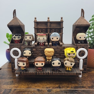Puede incluir: Un set de juego de castillo de Hogwarts de madera con 12 figuras de personajes de Harry Potter. El castillo tiene una sala del trono con dos sillas y una plataforma elevada con escalones. Las figuras incluyen Harry Potter, Ron Weasley, Hermione Granger, Dumbledore, Snape, y más.