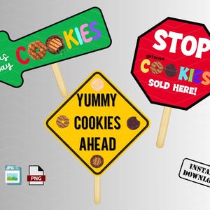 Puede incluir: Tres carteles imprimibles para un puesto de galletas Girl Scout. Los carteles son una flecha verde con las palabras "This Way" y "Cookies", un cartel amarillo en forma de diamante con las palabras "Yummy Cookies Ahead", y una señal de stop roja con las palabras "Girl Scout Cookies Sold Here!"