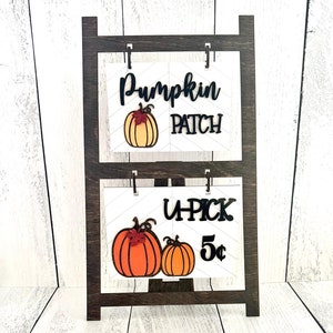 May include: A wooden stand with two signs. The top sign says "Pumpkin Patch" with a pumpkin graphic. The bottom sign says "UPick 5&cent;" with two pumpkin graphics.