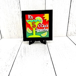 May include: A framed wood sign with a colorful illustration of a margarita glass and the text "It's 5 O'Clock Somewhere".