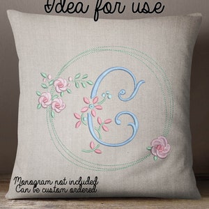Peut inclure: Un oreiller beige clair avec une lettre C brodée en bleu entourée d'un cercle vert et de fleurs roses. Le texte "Monogramme non inclus. Peut être commandé sur mesure" est en bas de l'oreiller.