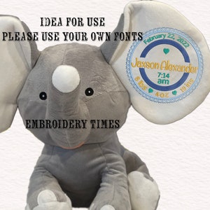 May include: Gray plush elephant toy with a white circle on its nose and black eyes. The elephant's ear has a blue and white embroidered circle with the text "Jaxson Alexander 7:14 am 8 lbs 4 oz 19 ins" and the date "February 22, 2022". The text "EMBROIDERY TIMES" is below the elephant.