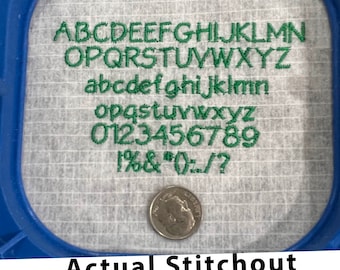 May include: A close-up of a white fabric with green embroidery showing the alphabet in uppercase and lowercase, numbers, and symbols. The fabric is in a blue embroidery hoop. A US dime coin is in the lower right corner of the image. The text below the hoop reads "Actual Stitchout 60 Weight Thread Font Size 7mm".