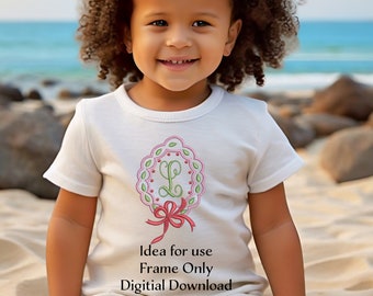 May include: A white shirt with a green and pink embroidered wreath with the letter L in the center. The wreath has a red bow at the bottom. The text "Idea for use Frame Only Digital Download" is printed below the wreath.