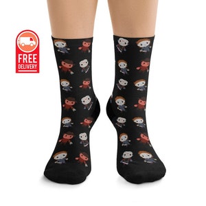 May include: Black socks with a pattern of cartoon horror movie characters. The characters include Freddy Krueger, Jason Voorhees, and Michael Myers.