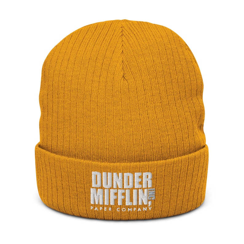 May include: A yellow knitted beanie with the text "Dunder Mifflin Paper Company" embroidered in white.