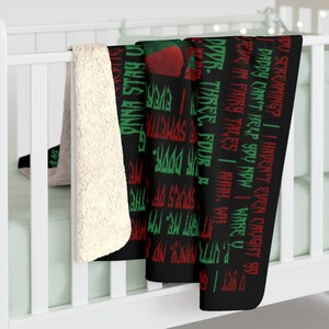 May include: Black and white throw blanket with red and green text. The text reads "DY SCREAMING? | I HAVEN'T EVEN CAUGHT YO DADDY CAN'T HELP YOU NOW | WAKEY WE'VE IN FAIRY TALES I AHHH, WILL PUTTI NANCY NO 99S. THREE, FOUR SOMETHIN' DOOR. SOULS OF THE NIGHT ME", and continues on the other side of the blanket.