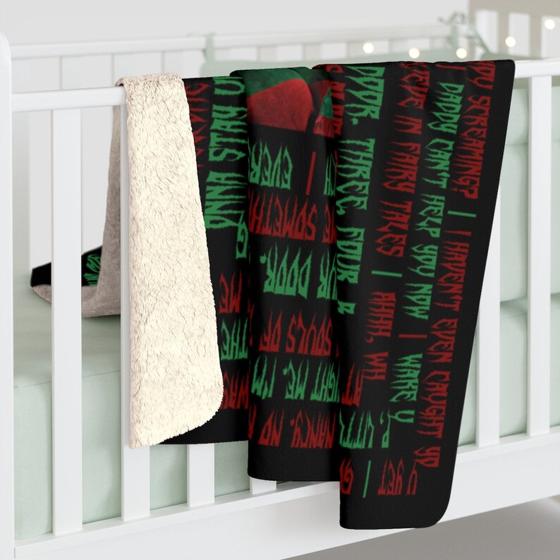 May include: Black and white throw blanket with red and green text. The text reads "DY SCREAMING? | I HAVEN'T EVEN CAUGHT YO DADDY CAN'T HELP YOU NOW | WAKEY WE'VE IN FAIRY TALES I AHHH, WILL PUTTI NANCY NO 99S. THREE, FOUR SOMETHIN' DOOR. SOULS OF THE NIGHT ME", and continues on the other side of the blanket.