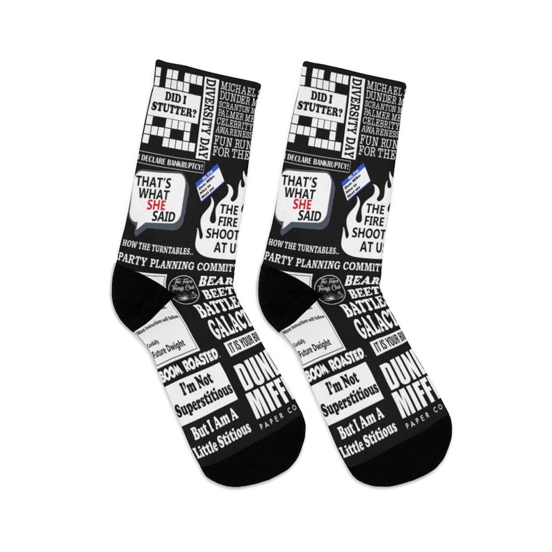 May include: A pair of black socks with a white print featuring text and images from the popular television show "The Office". The print includes quotes, characters, and scenes from the show. The socks are a fun and quirky way to show your love for the show.