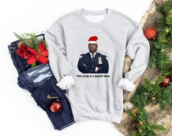 May include: A gray sweatshirt with a printed image of a man wearing a Santa hat and a police uniform. The text "This truly is a joyful time." is printed below the image.