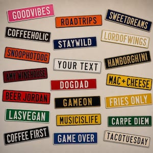 Może przedstawiać: Kolekcja prostokątnych metalowych tabliczek w różnych kolorach, każda z wytłoczonym tekstem, w tym GOODVIBES, ROADTRIPS, SWEETDREAMS, COFFEEHOLIC, STAYWILD, LORDOFWINGS, SNOOPHOTDOG, YOUR TEXT, HAMBORGHINI, AMY WINEHOUSE, DOGDAD, MAC+CHEESE, BEER JORDAN, GAMEON, FRIES ONLY, LASVEGAN, MUSICISLIFE, CARPE DIEM, COFFEE FIRST, GAME OVER oraz TACOTUESDAY.