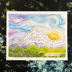 May include: Watercolor painting of a mountain range with a sun rising over the peaks. The quote "Even darkness must pass. A new day will come. And when the sun shines, it'll shine out the clearer." by J.R.R. Tolkien is written on the mountain.