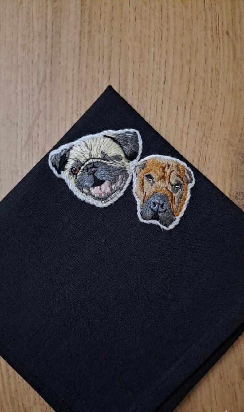 Black pocket square with an embroidered pug face and a brown wrinkle-faced dog, showing how a pet portrait stands out on dark fabric.