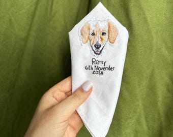 May include: White embroidered handkerchief with a dog's face and the text "Remy 6th November 2024".