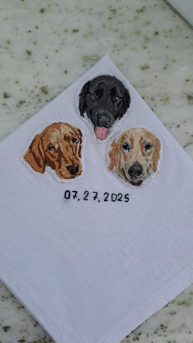 White pocket square with three embroidered dog portraits (a black Lab, a red retriever and a golden retriever) and a wedding date stitched underneath.