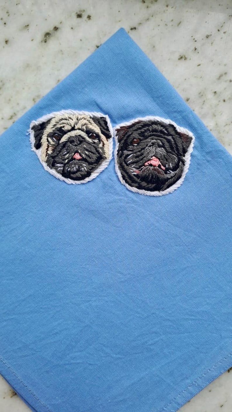 Light blue pocket square embroidered with two pug faces, one fawn and one black, an example of a two-pet portrait.
