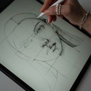 May include: A hand uses a stylus to draw a portrait of a woman on a digital drawing tablet. The woman's face is drawn in pencil and is divided into sections by a grid.