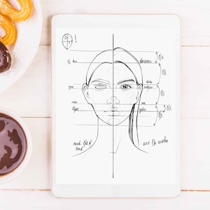 May include: A digital tablet displays a detailed sketch of a face, with labeled anatomical proportions. Beside it, a plate of churros, some dipped in chocolate, and a small bowl of chocolate sauce sit on a white wooden surface.