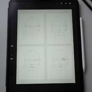May include: A digital drawing tablet displaying four different stages of a face drawing tutorial. Each stage shows a face with a grid overlay, with the final stage showing a more detailed face with shading and features.