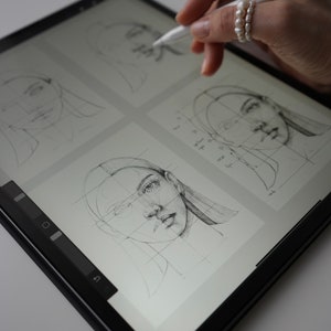 May include: A digital drawing tablet with a stylus, showing a gridded drawing of a face on the screen. The drawing is in progress, with lines and shading visible.