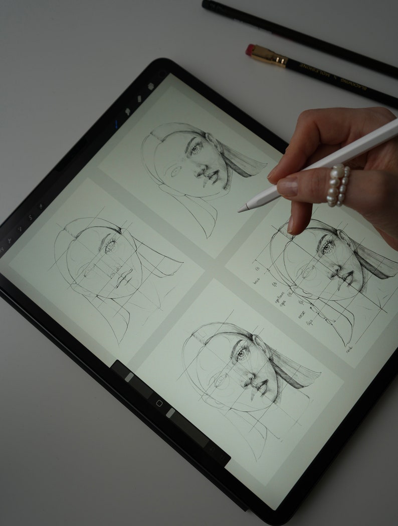 May include: A digital drawing tablet with a stylus pen, showing four different sketches of a woman's face. The sketches are drawn on a grid, and the stylus pen is being used to draw on the tablet.