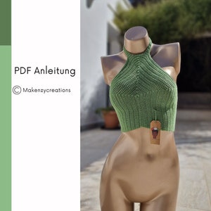 Könnte beinhalten: Ein grünes Häkel-Halter-Top auf einem Mannequin. Das Top hat ein schlichtes Design und ist kurz geschnitten. Das Top ist mit einem kleinen Etikett versehen, auf dem "PDF Anleitung" und "Makenzycreations" steht.