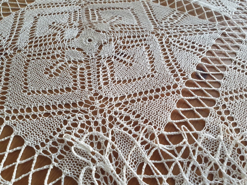 May include: White crocheted doily with a delicate, intricate pattern. The doily is made of fine thread and has a circular shape.