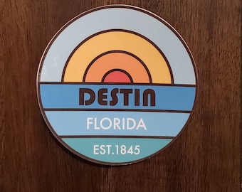 Könnte beinhalten: Ein runder Aufkleber mit einem blauen, türkisfarbenen und orangefarbenen Sonnenuntergangsdesign. Der Aufkleber lautet "Destin, Florida, Est. 1845".
