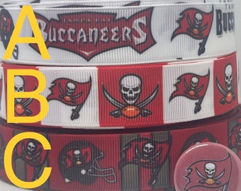 Op de afbeelding: Drie rollen rood, wit en zwart lint met een Tampa Bay Buccaneers logo. Het lint heeft een schedel en gekruiste beenderen ontwerp. Het lint is verkrijgbaar in 7/8" en 1,5" breed. Een rode, witte en zwarte knop met het Buccaneers logo is ook inbegrepen.