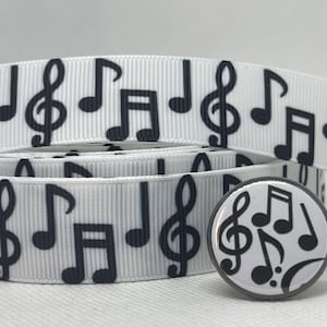 May include: White ribbon with black musical notes and a treble clef printed on it. A black and white button with musical notes and a treble clef is also included.