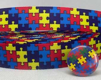 Może przedstawiać: Rolka wstążki z wzorem puzzli w kolorze niebieskim, czerwonym, żółtym i zielonym z dopasowanym guzikiem.