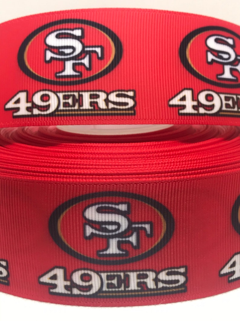 以下が含まれることがあります： サンフランシスコ・フォーティナイナーズのロゴと「49ers」の文字が印刷された赤と金のリボンです。