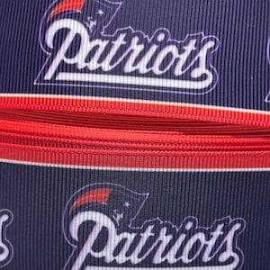 May include: Red, white, and blue ribbon with the word "Patriots" printed in white on a navy blue background.
