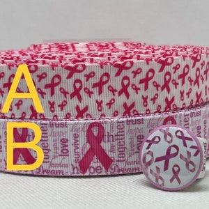 May include: Pink ribbon patterned ribbon with the words "Dream", "Hope", "Love", "Survive", "Fearless", "Trust", "Together", "We", "Believe", "Fight", "Hope", "Love", "Trust" printed on it. A pink ribbon button with the same pattern is also included.