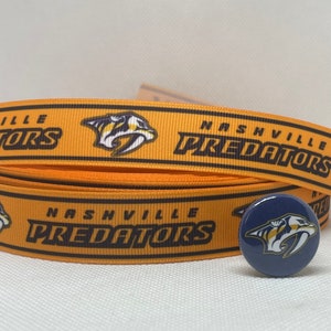 May include: Orange and black ribbon with the words "Nashville Predators" and a stylized predator bird logo. A blue button with the same logo is also shown.