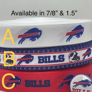 May include: Three rolls of ribbon in white, blue, and red, displaying the Buffalo Bills logo and text. The white ribbon has a blue and red logo. The blue ribbon has the word "BILLS" and a football helmet. The red ribbon has the word "BILLS" and a button with the logo.