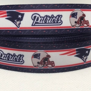 May include: A white, red, and blue ribbon with the words "Patriots" and a football helmet graphic.