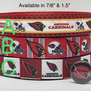 May include: Three rolls of red, white, and blue ribbon with the Arizona Cardinals logo and the text "Arizona Cardinals". The ribbon is available in 7/8 inch and 1.5 inch widths. A small red, white, and black button with the Arizona Cardinals logo is also shown.