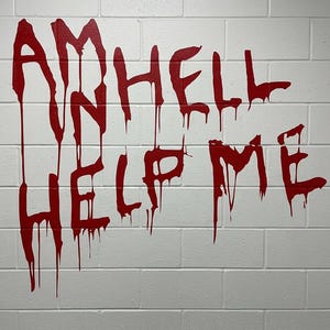 May include: A white brick wall featuring the text I AM HELL HELP ME written in a dripping, blood-red paint style. The letters are uneven and appear to be hand-painted, with vertical streaks of red paint running down from the characters onto the bricks.
