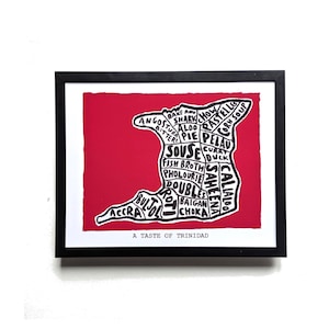 May include: A framed print featuring a red map of Trinidad divided into sections labelled with food names like Bake and Shark, Souse, and Doubles. The text A TASTE OF TRINIDAD appears at the bottom. The design uses black lines on a red background.