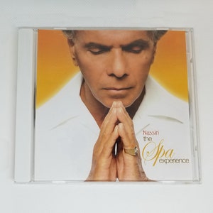 May include: CD cover featuring a man with his hands clasped in prayer. The background is a bright orange. The text on the cover reads "Nassiri the Spa experience".
