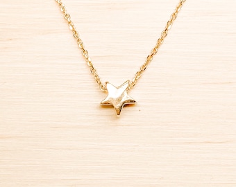 May include: A delicate gold chain necklace with a small, textured star pendant.