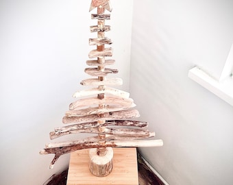 May include: A wooden Christmas tree made of driftwood branches, with a star on top, standing on a small wooden stool.