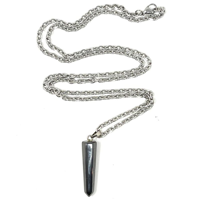 Op de afbeelding: Een zilverkleurige metalen ketting met een gladde, donkergrijze, langwerpige zeshoekige hanger. De hanger heeft een puntige onderkant en hangt aan een eenvoudig metalen oogje dat is bevestigd aan de gepolijste schakelketting met een karabijnsluiting.