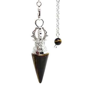 May include: A silver pendulum with a tiger's eye stone cone and a small tiger's eye bead on a chain. The pendulum features ornate silver detailing and is suspended from a chain.