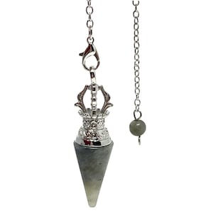 Op de afbeelding: Een zilverkleurige pendel met een grijze, kegelvormige kristal. De pendel heeft een decoratieve bovenkant en is opgehangen aan een ketting. Een aparte ketting met een kleine grijze kraal hangt in de buurt.